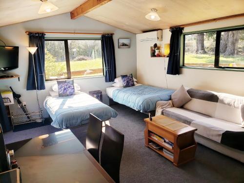 Height of Dunedin Serviced Farm Stay في دنيدن: غرفة معيشة كارافان مع أريكة وطاولة