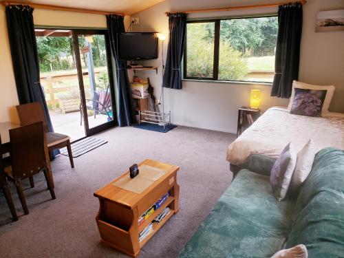 Habitación con cama, sofá y mesa. en Height of Dunedin Serviced Farm Stay en Dunedin