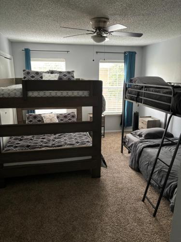 a room with two bunk beds and a ceiling fan at Hosting Nightly Nestings in Irving