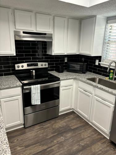 a kitchen with white cabinets and a stove top oven at Hosting Nightly Nestings in Irving
