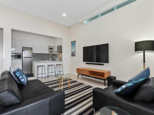 a living room with two black couches and a flat screen tv at Bare Feet Retreat in Kingscliff