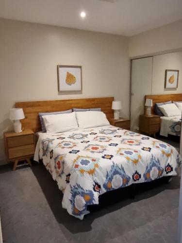 a bedroom with a bed with a comforter on it at Pleasant City Stay on Collins in Melbourne