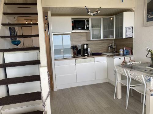 une petite cuisine avec des armoires blanches et une table dans l'établissement Duplex à 30m de la plage avec parking privé - FR-1-782-63, au Barcarès