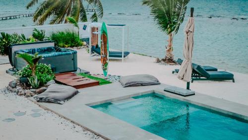 a swimming pool next to the water with an umbrella at Pension Irivai, Appartement RAVA 1 chambre bord de mer in Uturoa