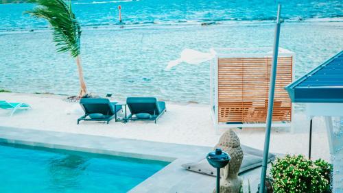 two chairs and a table next to a swimming pool at Pension Irivai, Appartement RAVA 1 chambre bord de mer in Uturoa