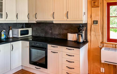 a kitchen with white cabinets and a black stove top oven at Nice Home In Malm With Lake View in Malm