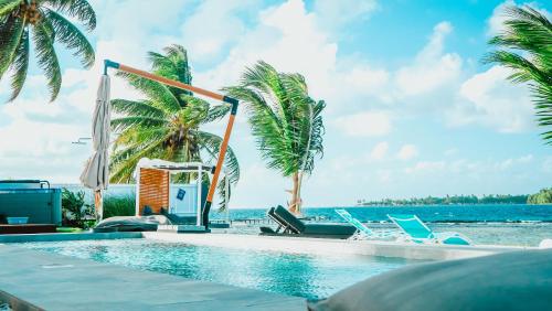 a swimming pool next to the ocean with palm trees at Pension Irivai, Appartement RAVA 1 chambre bord de mer in Uturoa