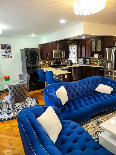 a living room with blue couches and a kitchen at Osas Luxury Stay in Queens