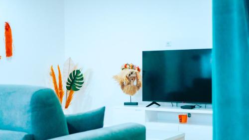a living room with a blue couch and a television at Pension Irivai appartement PUATOU 1 chambre bord de mer in Uturoa
