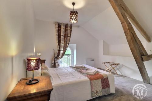 a bedroom with a bed and a table with a lamp at L'etang in Mézières-sur-Couesnon
