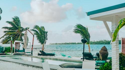 a resort swimming pool with chairs and a view of the water at Pension Irivai appartement PUATOU 1 chambre bord de mer in Uturoa
