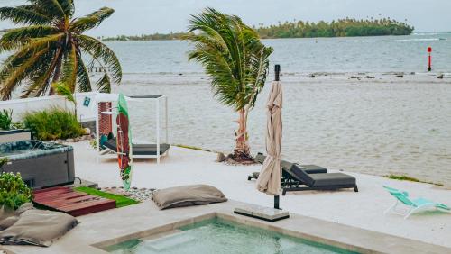 a swimming pool next to a beach with an umbrella at Pension Irivai appartement PUATOU 1 chambre bord de mer in Uturoa