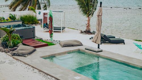 a swimming pool next to a beach with an umbrella at Pension Irivai appartement PUATOU 1 chambre bord de mer in Uturoa