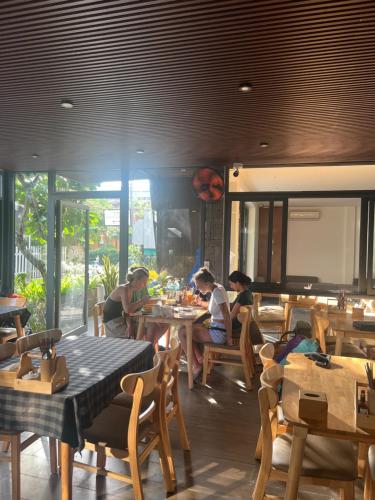 a group of people sitting at tables in a restaurant at Em's House Hoi An Homestay in Hoi An
