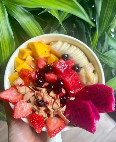 a person holding a bowl of fruit salad at Em's House Hoi An Homestay in Hoi An