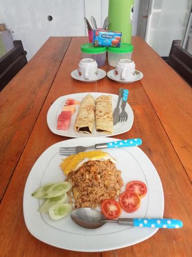 two plates of food on a wooden table at bulan homestay in Plambi