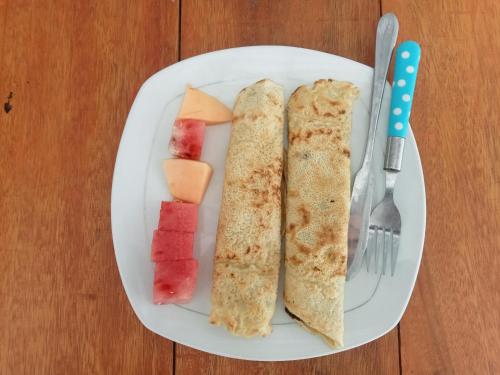 a white plate with a sandwich and fruit on it at bulan homestay in Plambi
