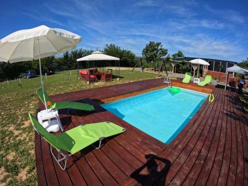 a pool on a deck with chairs and an umbrella at Sunny Side Fruska Gora -touristic estate in Velika Remeta