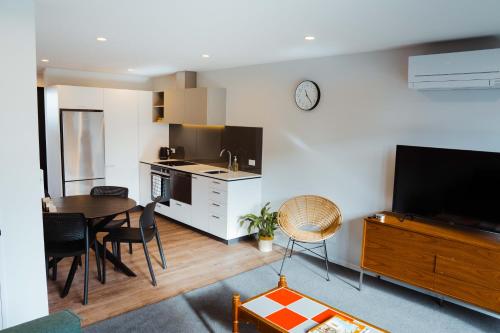 a kitchen and dining room with a table and a television at New townhouse, 300m 4 minute walk Te Kaha One New Zealand Stadium, car park, 2 bed 2 bath in Christchurch