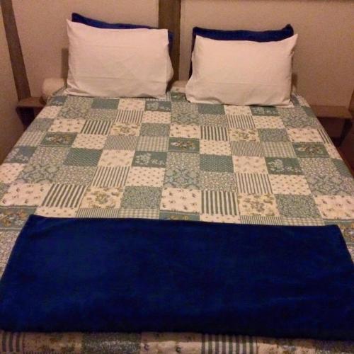 a bed with a quilt on it with two pillows at Chalés Musa de Maresias in Maresias