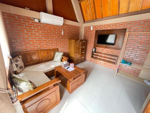 a living room with a couch and a brick wall at Villa Andhita Pantai Garut in Mancagahar