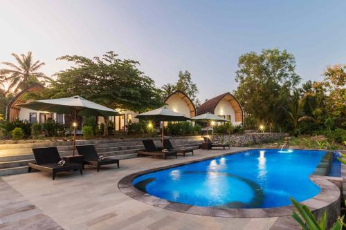 a pool at a resort with chairs and umbrellas at Jewel of Penida in Nusa Penida