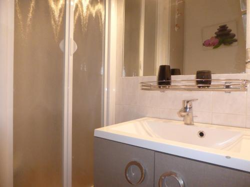 La salle de bains est pourvue d'une douche et d'un lavabo blanc. dans l'établissement Appartement Cosy avec Piscine, près du Lac de Tanchet et Plages, Les Sables-d'Olonne - FR-1-325-129, à Les Sables-dʼOlonne