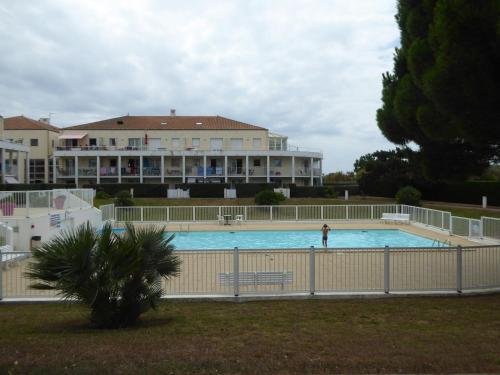 une personne debout dans une piscine en face d'un bâtiment dans l'établissement Appartement Cosy avec Piscine, près du Lac de Tanchet et Plages, Les Sables-d'Olonne - FR-1-325-129, à Les Sables-dʼOlonne