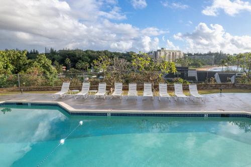 a swimming pool with a bunch of chairs at Banyan Harbor Resort in Lihue