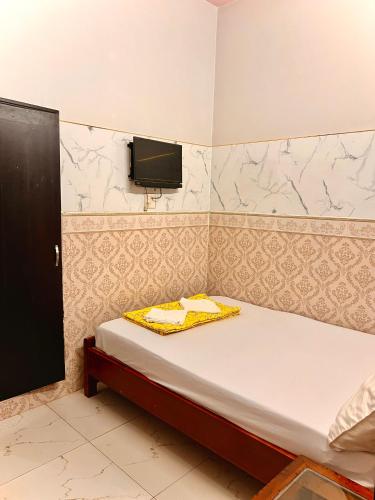 a small bedroom with a bed and a tv on the wall at Cao Nguyên Xanh in Bao Loc