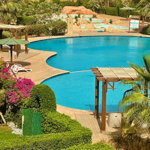 a large swimming pool with a wooden table next to it at Chalet in Bluebay Asia Resort Ain Sokhna in Ain Sokhna