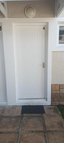 a white garage door on a white house at Cute condo with garden and BBQ in Plettenberg Bay