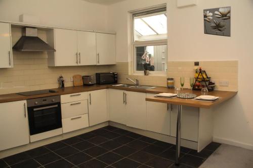 a kitchen with white cabinets and a wooden counter top at Spacious House, Near Haigh Woodland Park, Wifi, Parking in Leigh