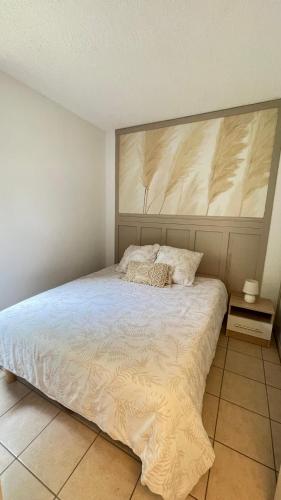 une chambre avec un grand lit avec une grande tête de lit dans l'établissement Rez-de-jardin Pinède Piscine Clim proche Plage Village naturiste, au Cap d'Agde