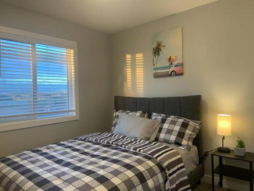 a bedroom with a bed with a checkered blanket and a window at Exquisite 3 BR Villa with Double Garage-King Bed in Regina