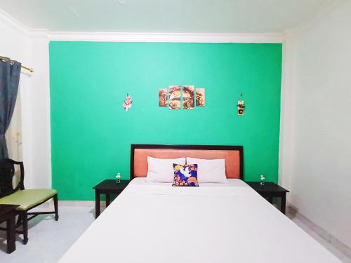 a bedroom with a white bed and a green wall at YUTAKA INN Global Juanda Sidoarjo in Kalangan