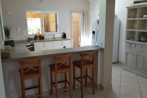 une cuisine avec deux tabourets de bar et un comptoir dans l'établissement Villa Olmeccia piscine 14 m, clim, plein Sud, à Porto-Vecchio