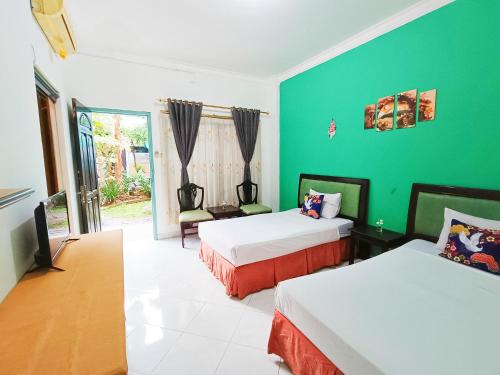 a room with two beds and a green wall at YUTAKA INN Global Juanda Sidoarjo in Kalangan