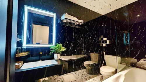 a black bathroom with a toilet and a sink at Rosa Hotel & Spa in Ho Chi Minh City