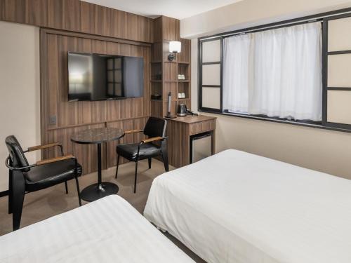 a hotel room with a bed and a table and chairs at Sunhotel Fukuyama in Fukuyama