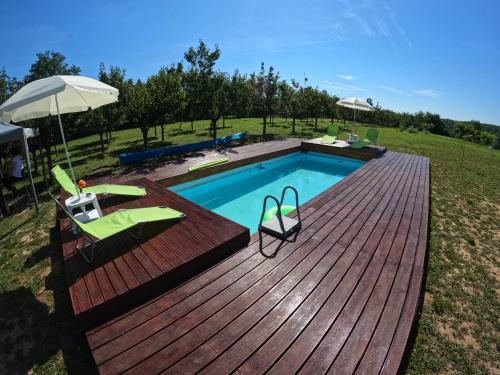a swimming pool on a wooden deck with an umbrella at Sunny Side Fruska Gora- apartman A in Velika Remeta