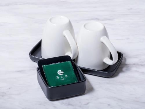 two white coffee mugs and a box on a table at Sunhotel Fukuyama in Fukuyama