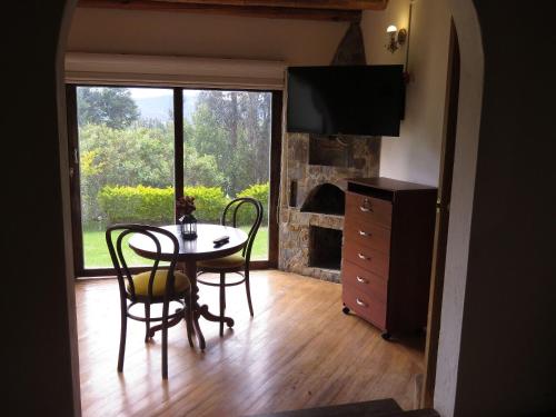 a dining room with a table and chairs and a fireplace at Chalet Campestre la Peseta in Ubaté
