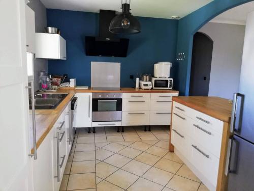 une cuisine avec des armoires blanches et un mur bleu dans l'établissement Villa victoria, à Cornillon