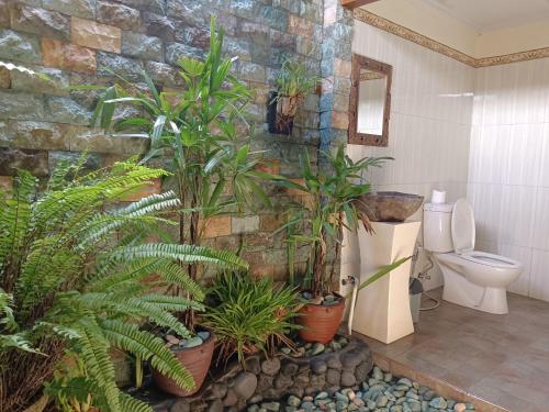 La salle de bains est pourvue de plantes et d'un mur en pierre. dans l'établissement Mancur Guesthouse, à Ubud