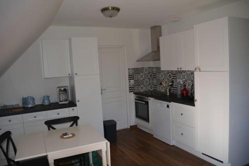 - une cuisine blanche avec des placards blancs et une table dans l'établissement Chez Catherine, à Branville