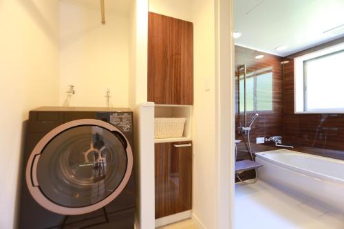 - un lave-linge dans la salle de bains à côté d'une baignoire dans l'établissement スターダストヴィラミルキーウェイ, à Fukai