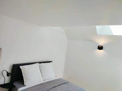 - une chambre blanche avec un lit et une lampe dans l'établissement Idéale pour ouvriers, proche d'Antony, Massy et Versailles, à Bièvres