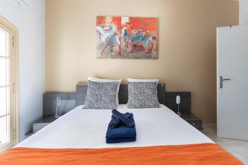 une chambre avec un grand lit blanc avec un chapeau bleu dessus dans l'établissement Au coeur de l'Isle, à LʼIsle-sur-la-Sorgue