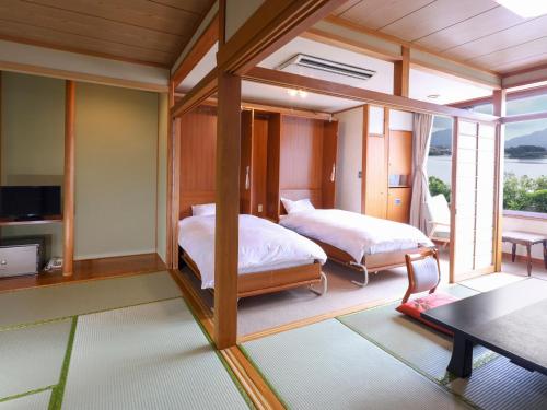 a bedroom with two beds and a tv in it at Hotel Koryu in Fujikawaguchiko